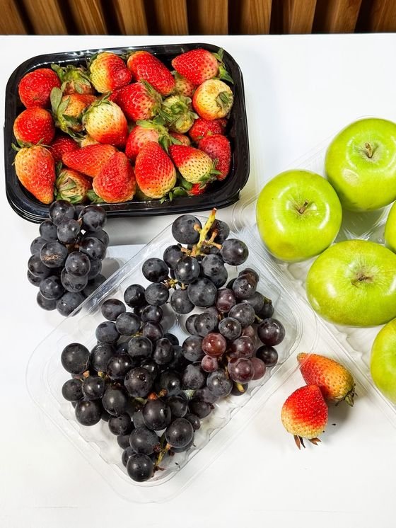 Fresas en bandeja negra y uvas en bandeja transparente